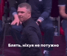 a man in a suit is kneeling down in front of a group of people with a caption in a foreign language