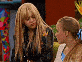two girls are sitting next to each other on a couch talking