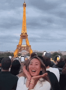 a woman stands in front of the eiffel tower laughing