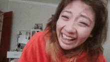 a woman wearing an orange shirt is making a funny face .