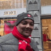 a man wearing a scarf and a beanie stands in front of a store called dior
