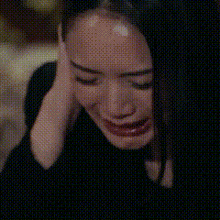 a woman is crying with her hand on her face and her eyes closed .
