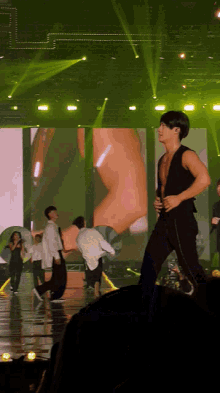 a man in a black vest is dancing on stage