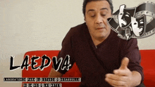 a man sitting on a red couch with the word laedva on the bottom right