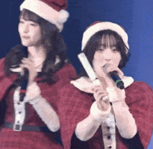 two girls in santa hats singing into microphones