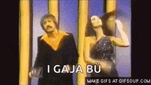 a man and a woman are dancing in front of a yellow wall and a sign that says `` i gaja bu '' .