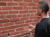 a man standing in front of a red brick wall