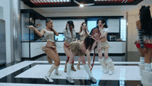 a group of women are dancing in a kitchen and one is wearing a plaid skirt