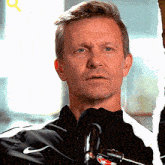 a man speaking into a microphone with a nike logo on his jacket