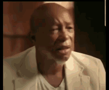 a man in a white suit is crying with his eyes closed and his mouth open .