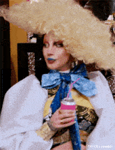 a drag queen is wearing a wig and holding a can of soda .