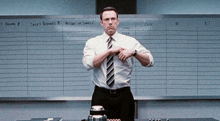 a man in a white shirt and tie is standing in front of a white board that says sales revenues