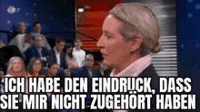 a woman is sitting in front of a crowd of people and talking to them in a foreign language .