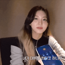 a woman holding a cell phone with korean writing on the bottom