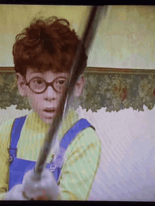 a young boy with red hair and glasses holds a sword
