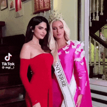 two women are posing for a picture and one has a sash that says universe on it
