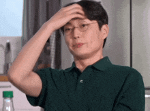 a man wearing glasses holds his hand to his head