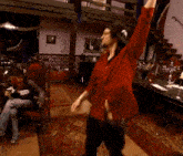 a man in a red shirt dancing in a room