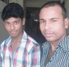a man in a plaid shirt stands next to another man in a black and white striped shirt