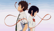 a boy and a girl are standing back to back with a red ribbon around their necks