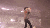 a man singing into a microphone on a stage with a soccer ball in front of him