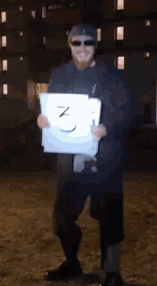 a man wearing sunglasses and a hat is holding a piece of paper with the number 3 written on it