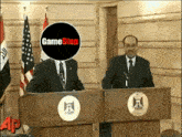two men at a podium with a game stop logo on their faces