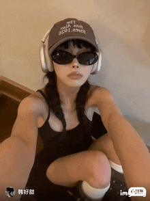 a woman wearing headphones and a hat that says " gift " on it is taking a selfie