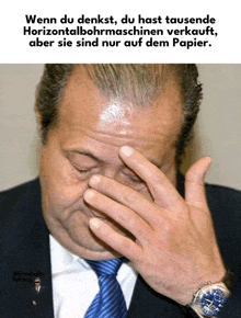 a man in a suit and tie covers his face with his hand