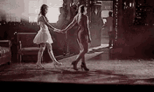 two women are dancing in a room holding hands .