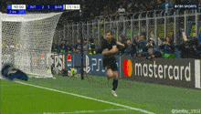 a man running on a soccer field with a mastercard banner behind him