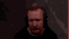 a man wearing headphones is sitting in a gaming chair in front of a red light .