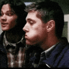 two men are standing next to each other and one of them is making a face .