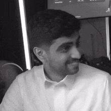 a man in a white shirt is smiling and looking at the camera