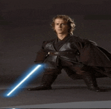 a young man in a star wars costume holds a light saber