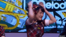 a woman wearing headphones is dancing in front of a large screen with the word melody on it .