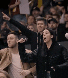 a woman wearing a nike jacket is screaming in a crowd of people