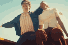a man and woman are sitting next to each other with their arms outstretched and smiling .
