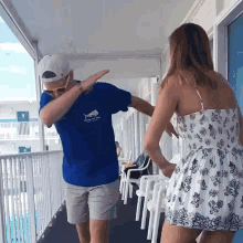 a man wearing a blue shirt with a shark on it is dancing with a woman