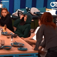 a woman in a green hoodie sits at a table with others