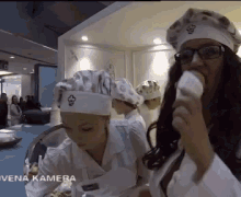 a woman wearing a chef 's hat is eating a cupcake