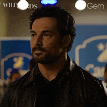 a man with a beard is standing in front of a sign that says wildcards gem