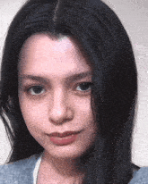 a woman with long black hair is looking at the camera