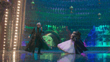 a man and a woman are dancing in front of a wall of lights