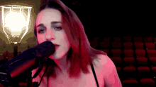 a woman singing into a shure microphone in front of an auditorium