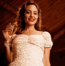 a woman in a white dress is holding a wine glass