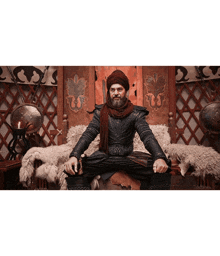 a man with a beard is sitting on a throne with his legs crossed