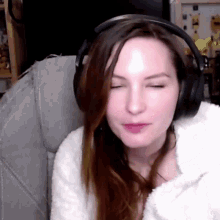 a woman wearing headphones looks at the camera with her eyes closed