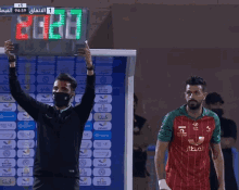 a man wearing a mask holds up a scoreboard that says 20:18