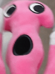 a close up of a pink stuffed animal with a black hole in its mouth